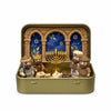 A gold-colored storage tin holds a nativity scene figurine set featuring figures and an arched backdrop with a menorah.