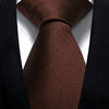 A close-up of a dark brown, textured silk necktie worn against a black suit jacket.