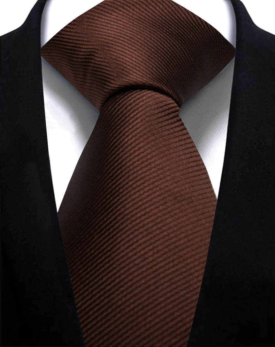 A close-up of a dark brown, textured silk necktie worn against a black suit jacket.
