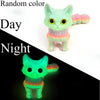 A 3D printed cat figurine with an articulated tail, shown in a light mint green color under dark lighting.