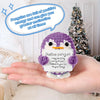 A handcrafted purple crochet penguin plush with an encouraging card is held in a person's hand.