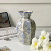 A hand-painted blue and white porcelain vase set displayed on a white table next to a laptop and a keyboard.