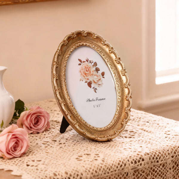 A vintage resin photo frame with golden ornamental details, featuring a floral design, displayed on a lace tablecloth.