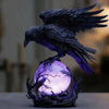 A dark raven sculpture with purple glow perched on a base.