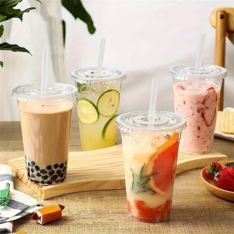 Three colorful iced beverages in clear plastic cups with straws are displayed on a wooden board.