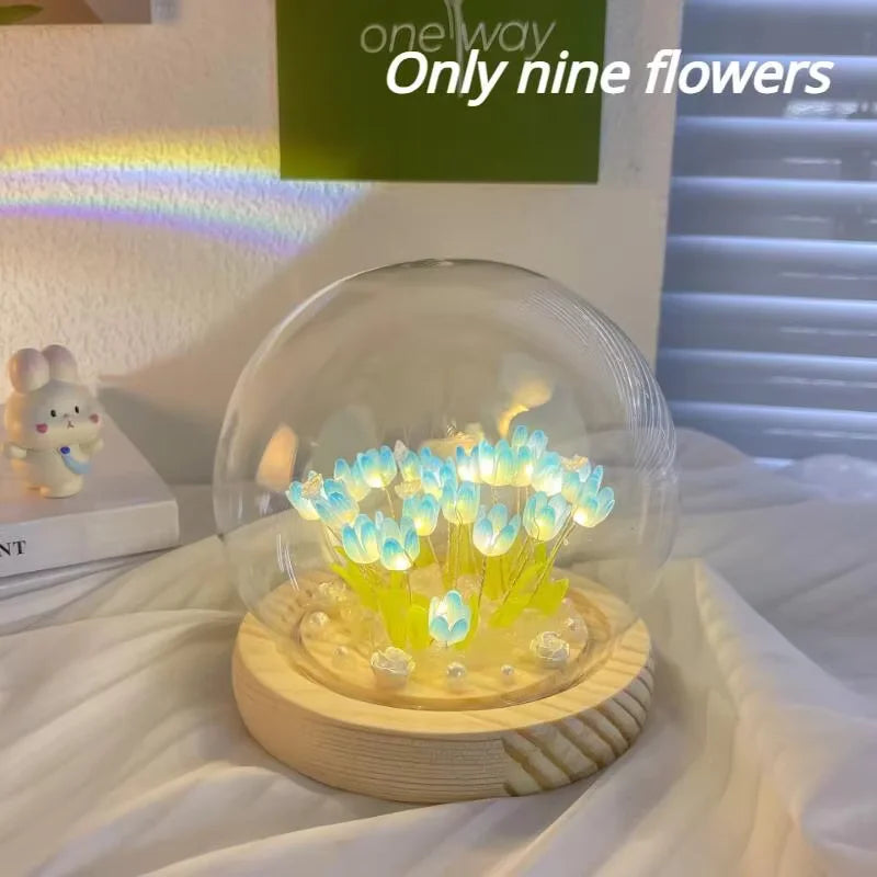 A clear glass dome containing nine glowing blue LED tulips on a wooden base.