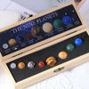 A wooden box containing a set of nine natural crystal gemstone spheres representing the nine planets in the solar system.