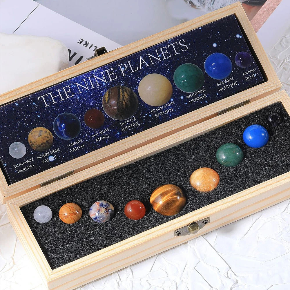 A wooden box containing a set of nine natural crystal gemstone spheres representing the nine planets in the solar system.