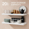 A display of glass mugs, gold canisters, and a black teapot on white floating wall shelves.