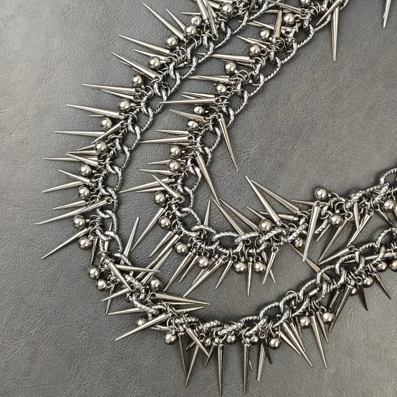 A close-up of a heavy punk rivet biker style chain necklace made of silver metal spikes.