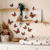 A display of twelve orange and black monarch butterfly wall decals arranged on wooden shelves and a white surface.
