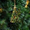 Un ornement étoile dorée pend sur une branche de pin verte décorée de petites baies vertes et rouges.