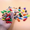 A hand holds a collection of colorful 3D printed cartoon animal figurines and toys on a light orange background.