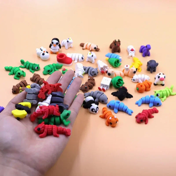 A hand holds a collection of colorful 3D printed cartoon animal figurines and toys on a light orange background.