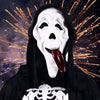A white and black horror mask resembling a screaming skeleton with a long tongue, shown against a dark, sparkling background.