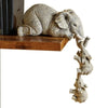 A resin figurine set of a large elephant hugging several smaller baby elephants.