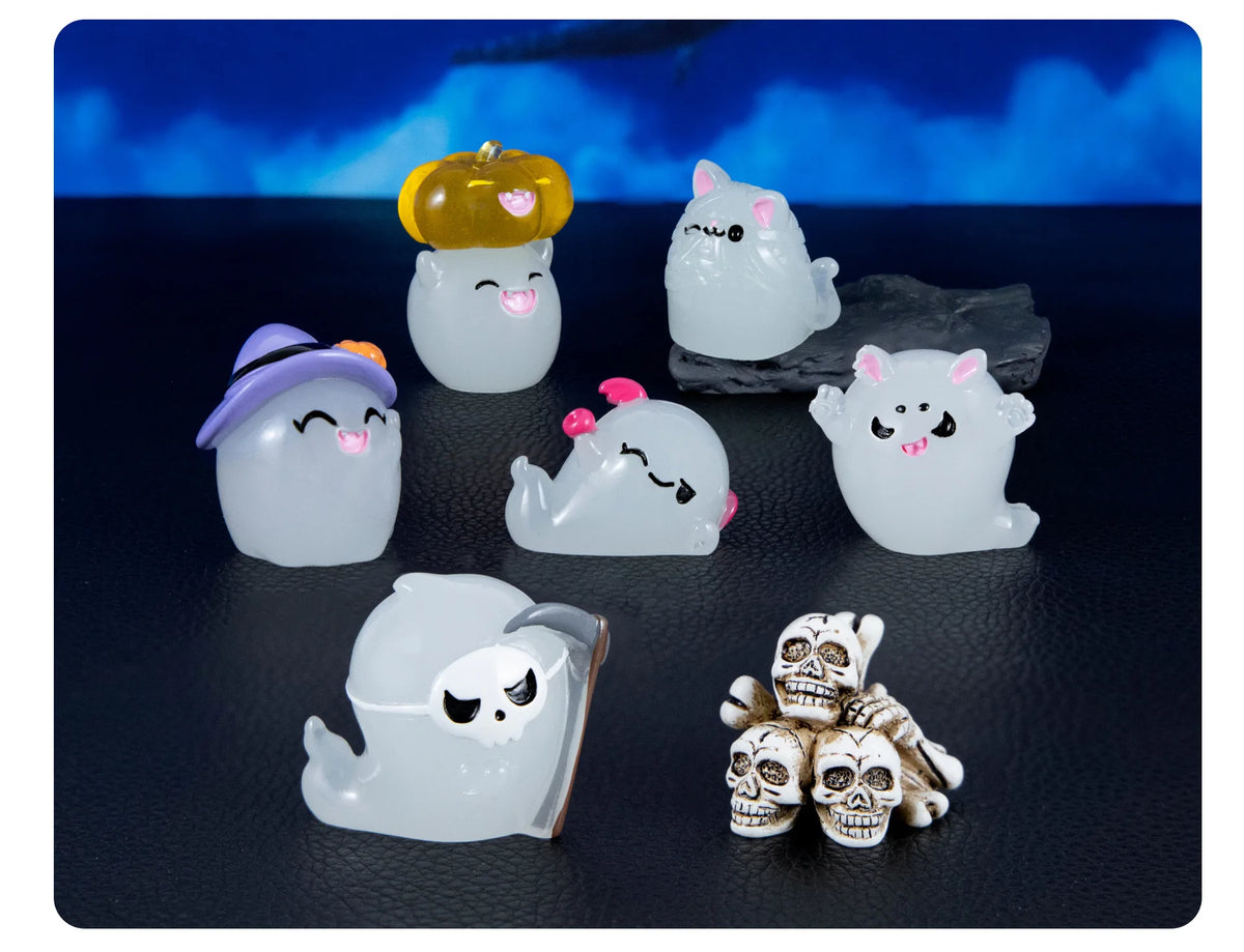 A collection of seven cute luminous ghost resin ornaments in various colors and shapes displayed on a dark surface.