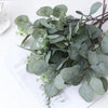 A lush green artificial eucalyptus stem with small white flowers displayed on a white background.