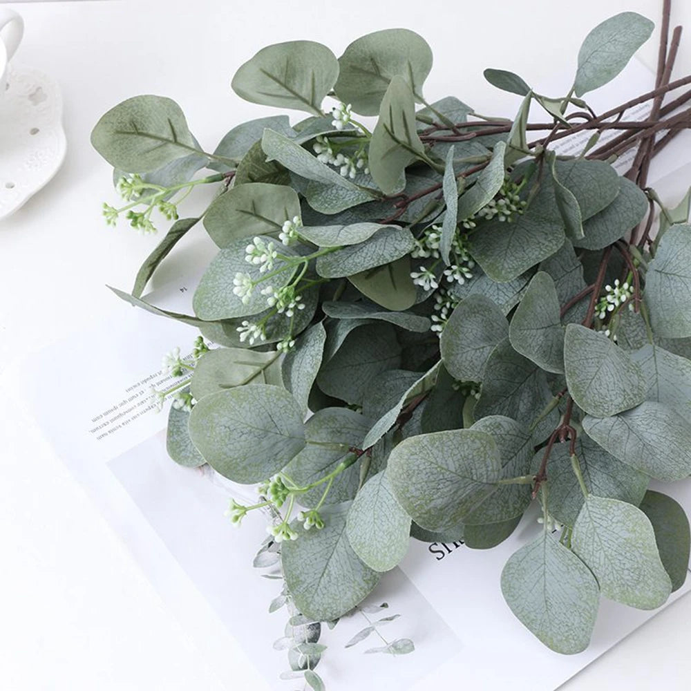 A lush green artificial eucalyptus stem with small white flowers displayed on a white background.