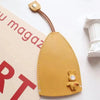 A tan cartoon PU leather key holder with a pull-out design attached to a brown leather cord.