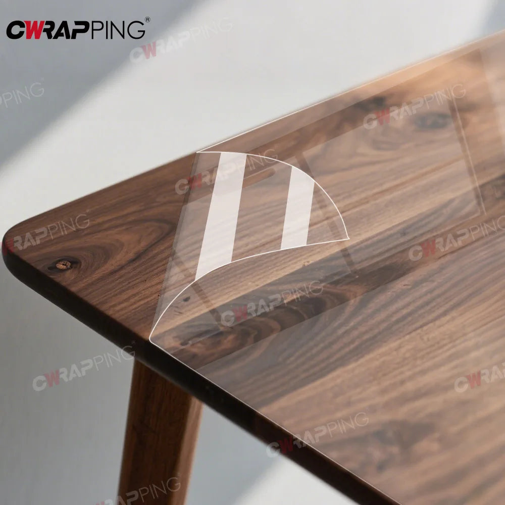 A close-up view of a wooden table surface protected by a clear, transparent film that features a white stripe design.