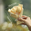A hand holds a bouquet of handmade yellow crochet flowers wrapped in light beige paper.