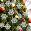 A close-up of a green Christmas tree decorated with white snowflake ornaments and gold accents.
