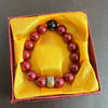 A bracelet of polished red cinnabar stones is displayed in a yellow velvet box.
