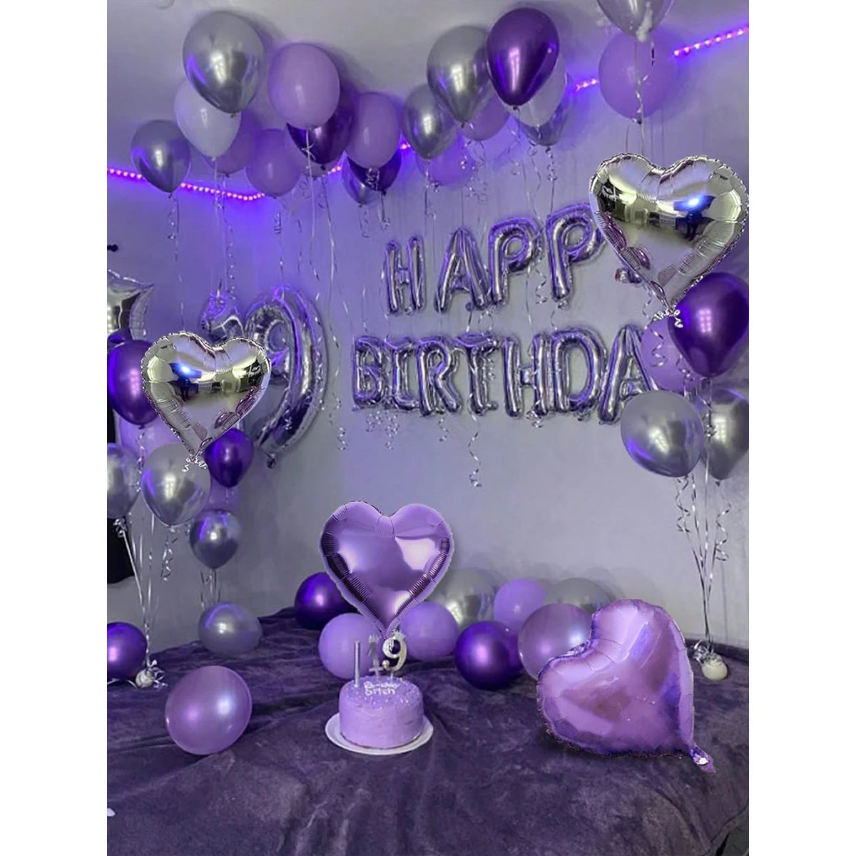 A purple and silver birthday decoration featuring metallic and heart-shaped balloons and a large lettering sign.