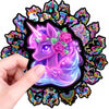 Una mano sostiene una calcomanía autoadhesiva de unicornio morado con acentos rosa y morado, con forma de caballo arcoíris de