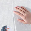 A hand is shown pressing a white, textured wallpaper panel to demonstrate the seamless stitching and thickness of the product
