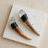A natural crystal Herkimer scepter wand with a dark handle rests on a white square tile.