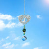 Silver crystal tree of life pendant with colorful gemstone drops suspended against a bright blue sky