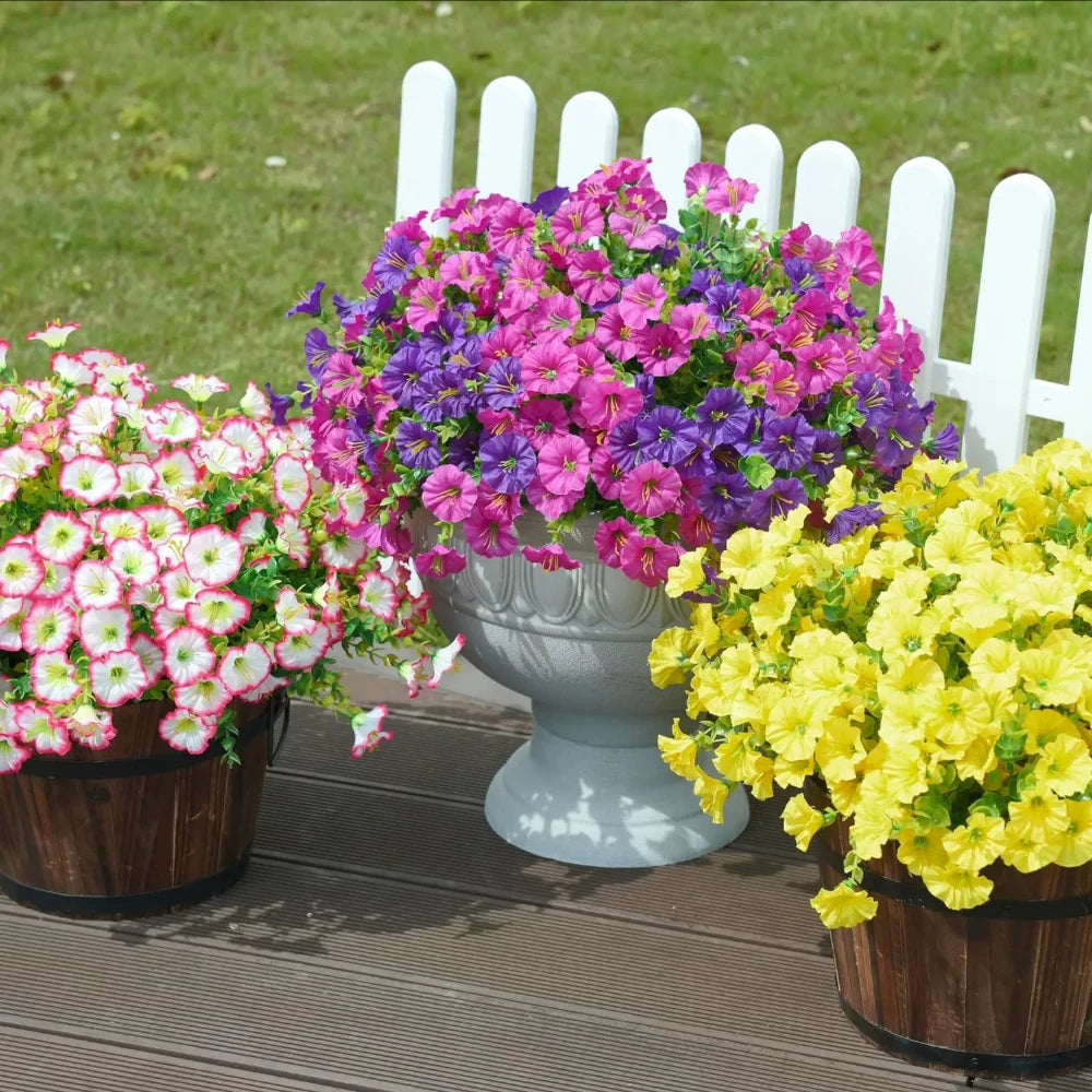 A vibrant bouquet of artificial flowers featuring purple, pink, and yellow blooms displayed in white planters.