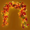 An archway made of artificial autumn maple leaves in shades of orange, red, and yellow.