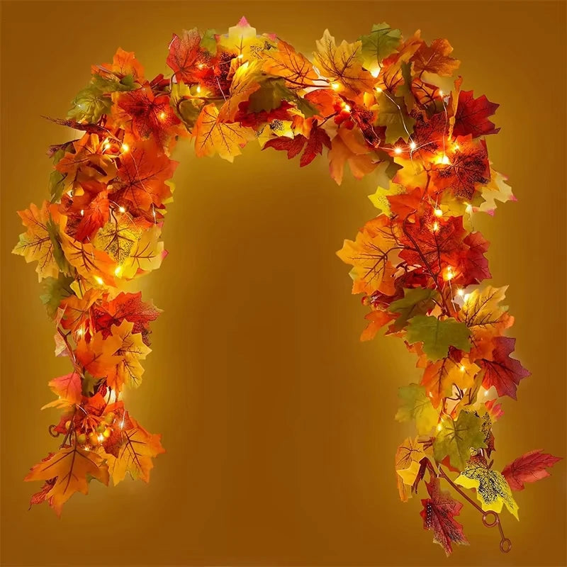 An archway made of artificial autumn maple leaves in shades of orange, red, and yellow.