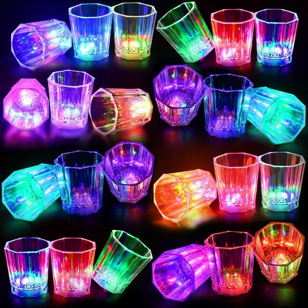 A collection of various shot glasses and tumblers illuminated with colorful LED lights for parties