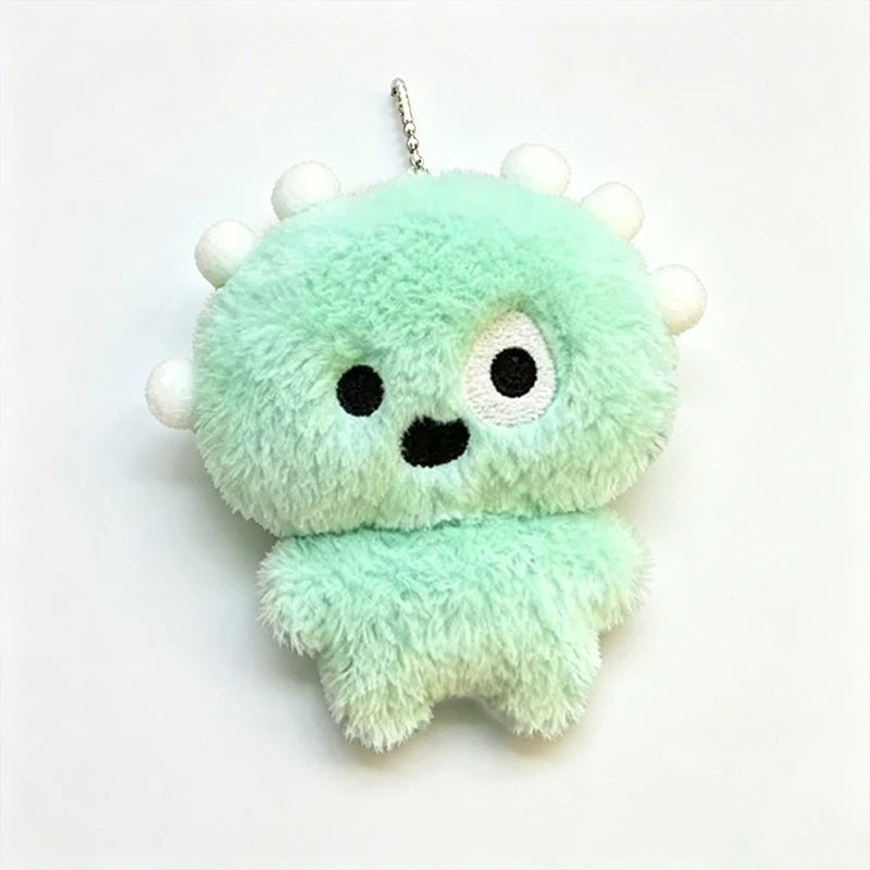 A light green fluffy plush keychain shaped like a monster with white horns and black eyes.