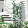 Artificial ivy garland climbing a white wooden fence or siding for outdoor garden decor