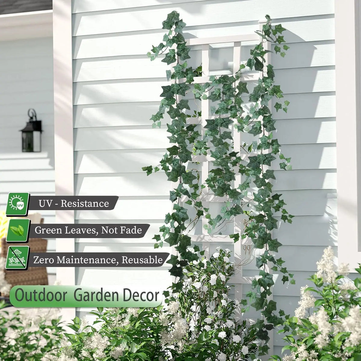 Artificial ivy garland climbing a white wooden fence or siding for outdoor garden decor