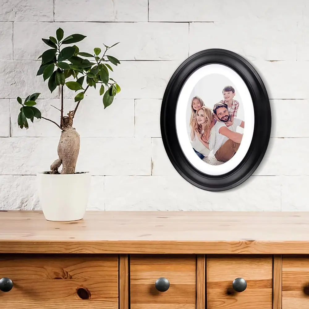 A classic solid wood oval picture frame with a light interior is displayed on a wooden cabinet top next to a potted plant.