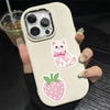 A hand holds a white phone case decorated with pink cartoon stickers of a kitten and a strawberry.
