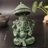A small, green bronze Ganesha Buddha statue with a tiered crown sitting on a dark surface.