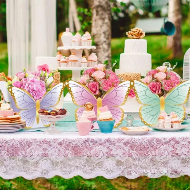 A table decorated for a butterfly garden party featuring pink and green cupcakes, macarons, and floral arrangements.