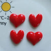 A set of four glossy red heart-shaped fridge magnets displayed on a white surface next to a yellow sun graphic.