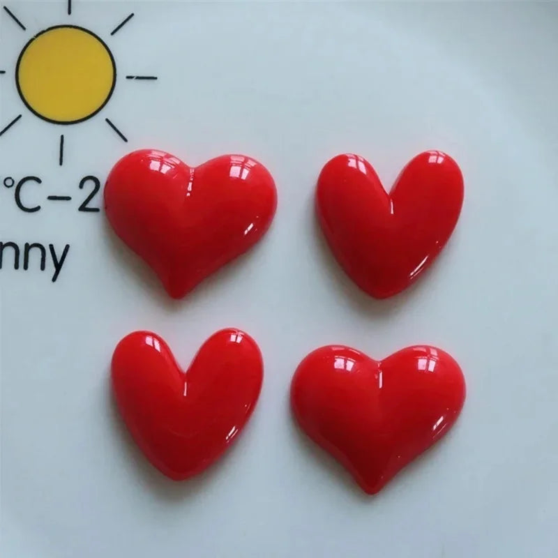 A set of four glossy red heart-shaped fridge magnets displayed on a white surface next to a yellow sun graphic.