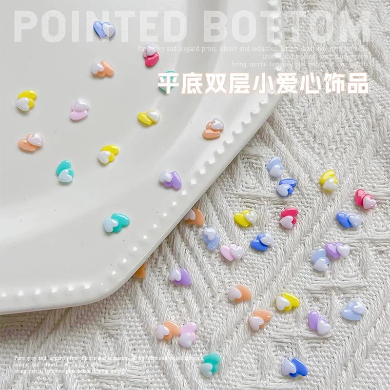 Un plato blanco contiene 50 adornos de uñas en forma de tortuga mini y coloridos, esparcidos sobre un paño blanco texturizado