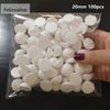 A hand holds a clear plastic bag filled with 100 white polystyrene foam balls, 20mm in diameter.
