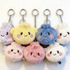 A collection of pink, yellow, and blue plush butter dumpling squishy keychains hanging from metal split rings.