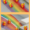 A set of mini resin colorful duck decorations arranged on a rainbow-colored surface.